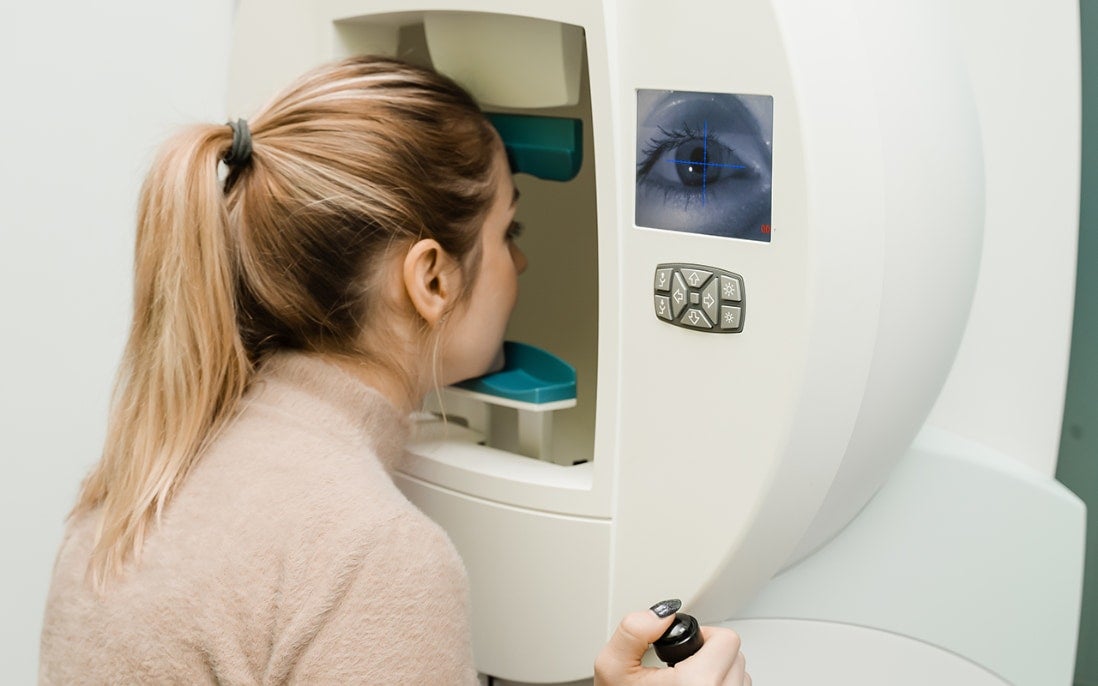 Ung kvinne som får sjekket synsfeltet med automatisk perimetri
